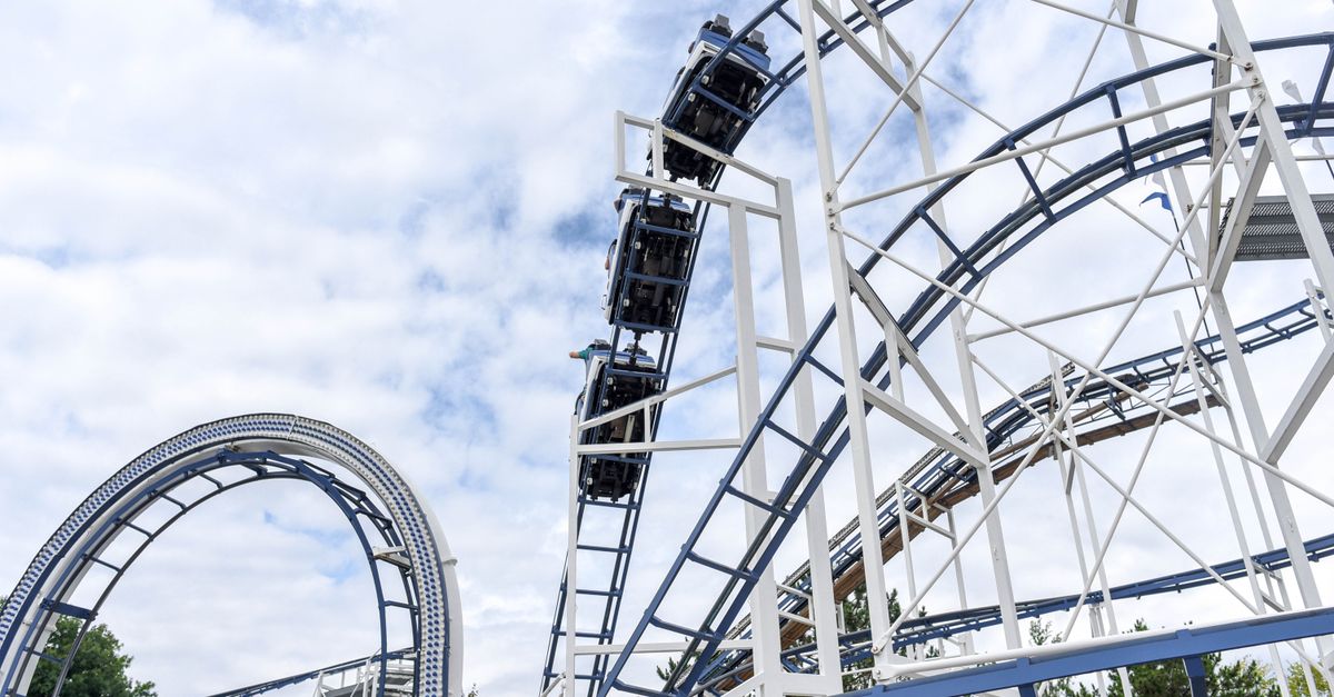 Experience the adrenaline rush of a steel roller coaster under blue skies at an amusement park.